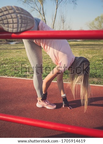 Young Athletic Woman Stretching Legs on Wall Bars in the Park