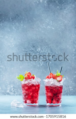 Red cocktail with ice and mint. Bar concept. Strawberry mojito with mint and ice on the blue background, selective focus image