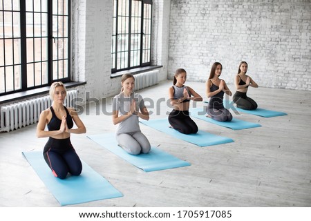 Group young woman practicing yoga in gym. People meditating at health club.