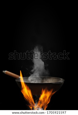 Empty wok pan with smoke above fire with sparks against black background. Cooking concept. Mockup, template for your collage, text, images. Close up