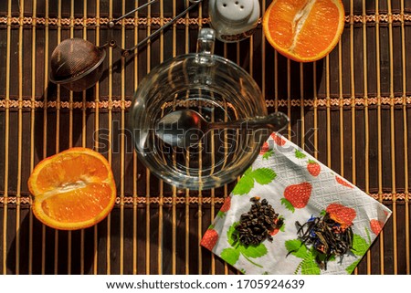 Flat Lay. Composition. Object photo.  Orange, glass cup spoon with sugar, tea on a napkin with the image of strawberries on a brown background on a sunny day, top view