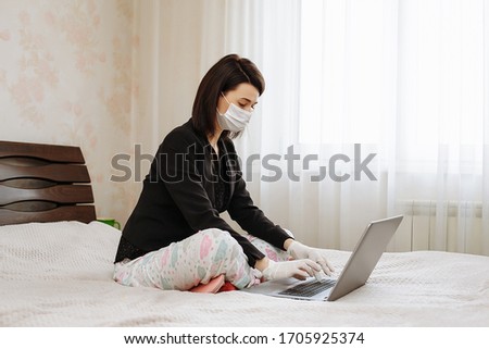 Woman in mask and jacket works at home at remote work.