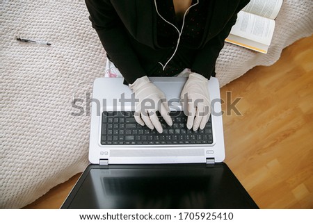 Masked woman in gloves working on laptop.