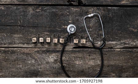 Covid 19 sign spelled on wooden blocks with medical stethoscope placed around it. Over rustic wooden background.