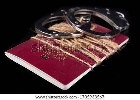 A passport tied with string and handcuffs. No travel during pandemics. Dark background.