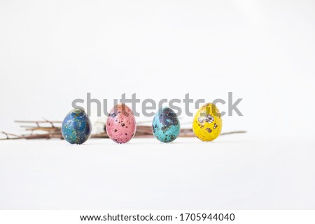 Four beautiful colored eggs lie on a white background with twigs. Spring holiday for the whole family