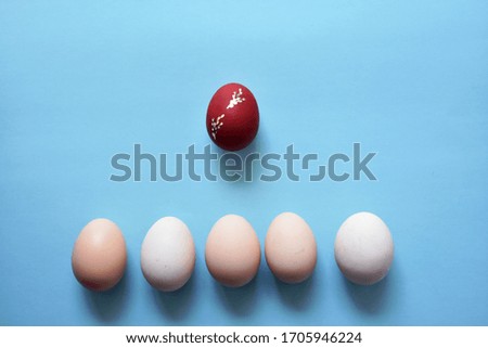 White Easter eggs on blue minimalist background with one egg on red color.Easter Element.Top View,Flat lay,copy space.
