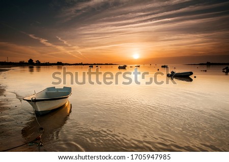 A sunset over a body of water with boat in first place
