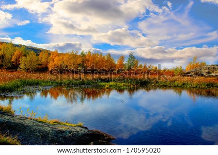 Lake in autumn forest under swimming by clouds Royalty-Free Stock Photo #170595020