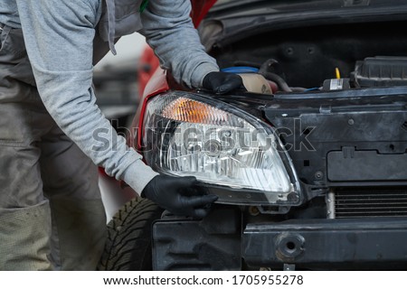 Auto service. Technician assembling an automobile headlight lamp. bodywork repair for insurance Royalty-Free Stock Photo #1705955278