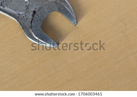 Macro photo of an old dirty metal wrench on a wooden table background.