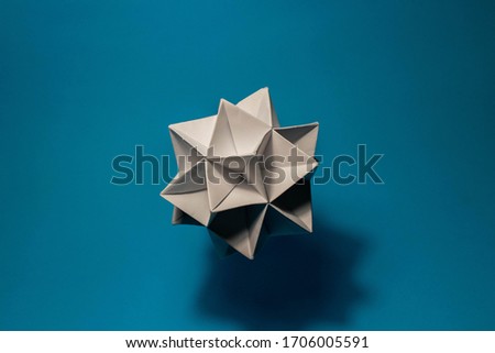 Isolated complex origami sculpture Kusudama floating in mid air with blue background