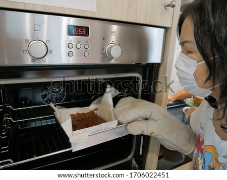 asian aging woman wearing mask cooking and baking at home. stay home, quarantine, self isolation, social distancing, shutdown, covid-19, pm2.5 concept 