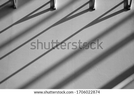 Wall with soft diagonal shadows from ceiling girders. Striped structure. Black and white photo of building interior fragment. Abstract architectural or industrial background in chiaroscuro technique.