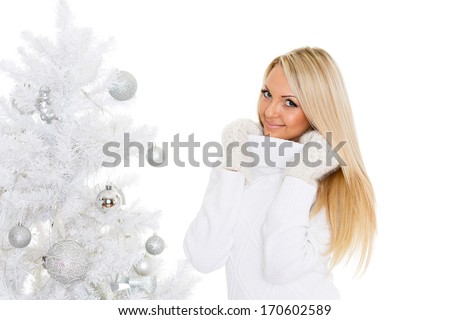 Young happy beautiful  woman in winter clothes stands near Christmas tree on a white background.