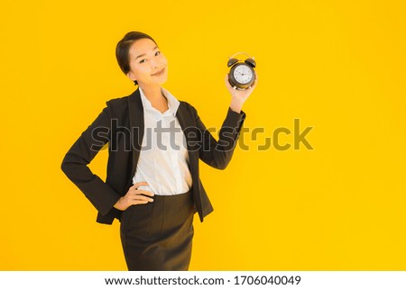 Portrait beautiful young asian woman show time of clock or alarm on yellow isolated background