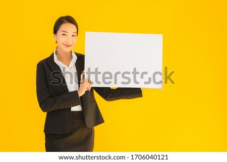 Beautiful portrait young asian woman show empty blank white board on yellow isolated background