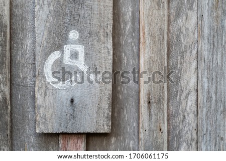 Vintage wood disabled wheelchair restroom sign on wooden wall bathroom door.