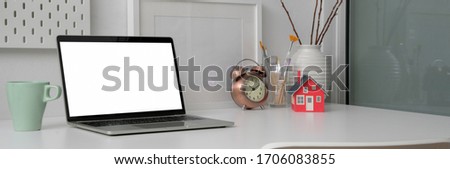 Cropped shot of trendy office desk with blank screen laptop, mug, decorations and copy space on white table