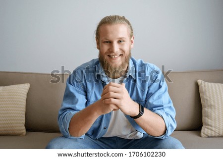Smiling millennial hipster guy blogger looking at camera video calling, recording vlog. Happy young man distance chatting at home office, streaming sitting on sofa. Headshot portrait. Webcam view Royalty-Free Stock Photo #1706102230
