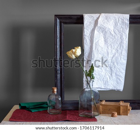 Still life with roses, bottles, picture frame and colored paper. Vintage. Retro.