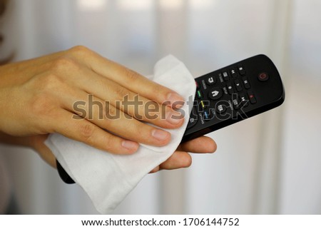 COVID-19 Pandemic Coronavirus Woman Cleaning with Wet Wipes TV Remote Control Disinfect Against Coronavirus Disease 2019 Outbreak Contamination Prevention. Royalty-Free Stock Photo #1706144752