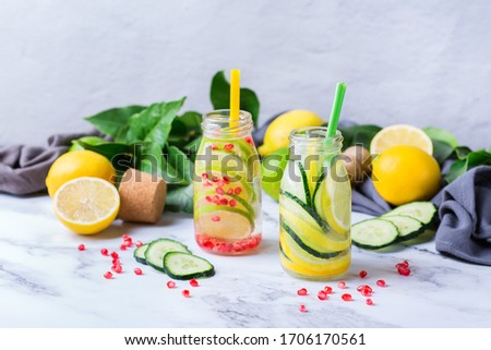 Health care, fitness, healthy nutrition diet concept. Fresh cool lemon cucumber rosemary pomegranate infused water, detox drink, lemonade in a glass jar for spring summer days. 