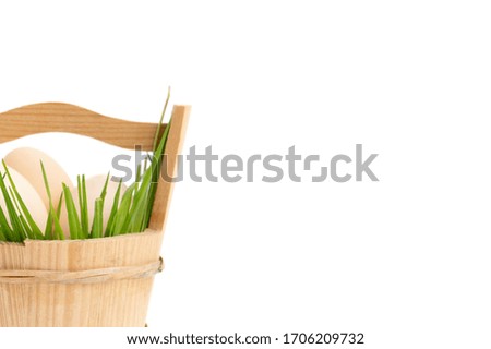 Easter eggs in a basket in the green grass, large-format banner, part of the basket on a white background.