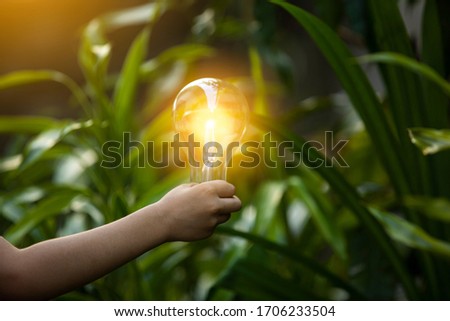Business man holding light bulb on the Green background nature and writing on note book it for financial