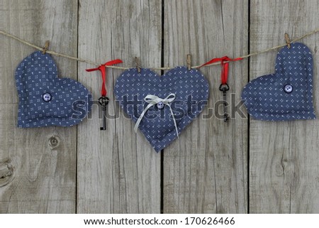 Blue calico hearts and iron keys hanging on clothesline with wood background