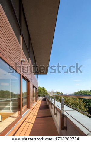Long balcony in wooden facade building with big window doors