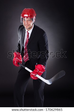 Portrait Of A Mature Businessman Dressed As Hockey Player Over Black Background