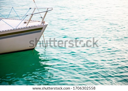 Ship's bow and aquamarine water, lake Garda. Boat and sea, detail. Sailing vessel drops anchor in a quiet bay