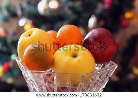 glass vase with fruits on a background of festive Christmas tree