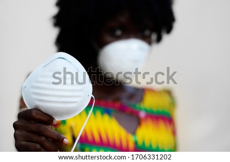 Close Up Of African Nurse Wearing Face Mask and giving Facemasks to Patients Royalty-Free Stock Photo #1706331202