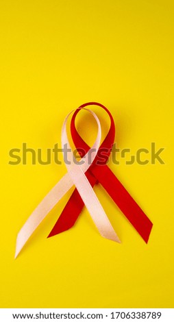 Pink and red ribbon isolated on yellow background.