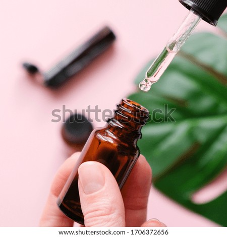 Essential oil falling from a glass dropper on the background of other medications