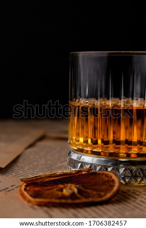 transparent glass of rye pure whiskey, on pages from books, on a dark background