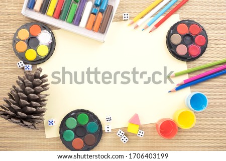 Color paints, pencils, a pinecone and a blank paper with free copy-space for text.
