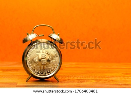 Concept  deadline to invest in cryptocurrency showing alarm clock with a bitcoin as the clock face on wood table