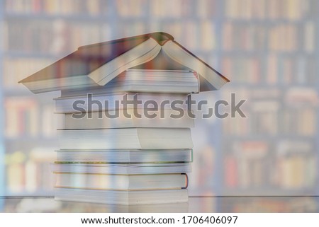 Stay at home and reading concept, In times of Coronavirus disease (COVID-19) scourge, Double exposure of stacked books in house shaped with blurred bookshelf, Hobby, Leisure activities.