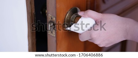 Young Asian woman adult opening door with clean tissue on the knob handle instead of hand, concept of antibacterial, virus prevention, close up.