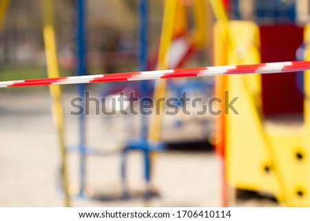An empty playground without children. Cut off with a striped red and white warning tape. Limitations quarantined for Covid-19 coronavirus.
