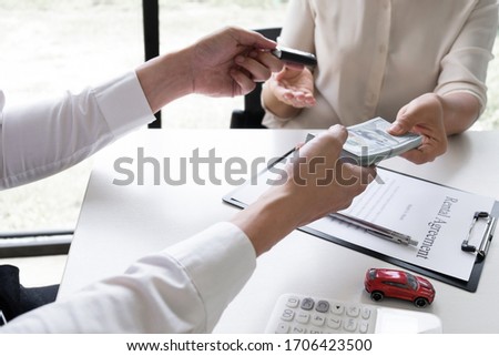 Customer is paying the rental fee to car rental representative after signed a car rental agreement in the office, Car rental concept.