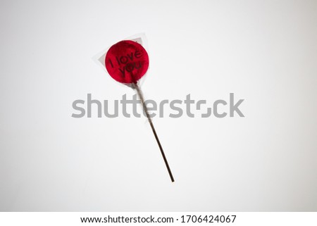 a sweet wrapped "I Love you" red transparent lollypop against a bright white background, flat lay, top view