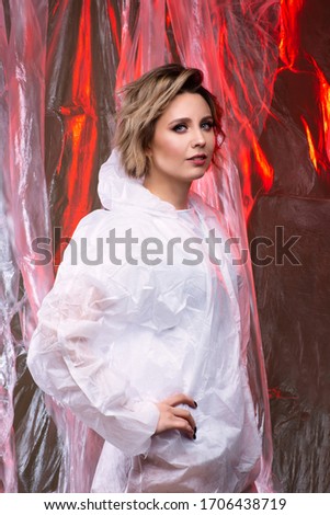 Beautiful model on the background of cellophane with red light, art photography, red lips, the beauty of lipstick. Beautiful scientist woman, world problem of cellophane pollution