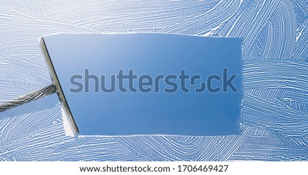 Rubber squeegee cleans a soaped window and clears a stripe of blue sky, concept for tranparency or spring cleaning, with copyspace for your individual text. Royalty-Free Stock Photo #1706469427