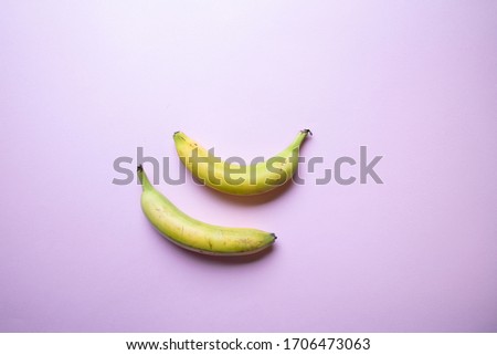 a stylish pastel coloured image of two bananas an a pink background, flat lay, top view