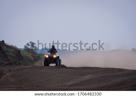 The quad racer is riding on the dirt road. Quad bike off-road. Quad bike in action
