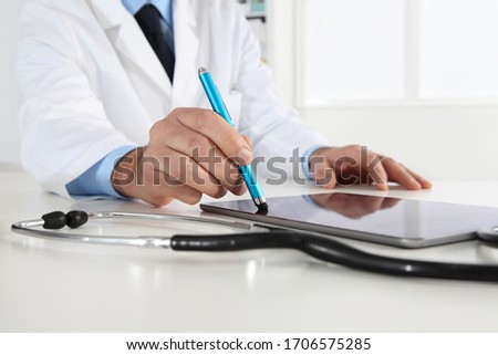 doctor hand touch screen of digital tablet writing prescription at desk in medical office close up